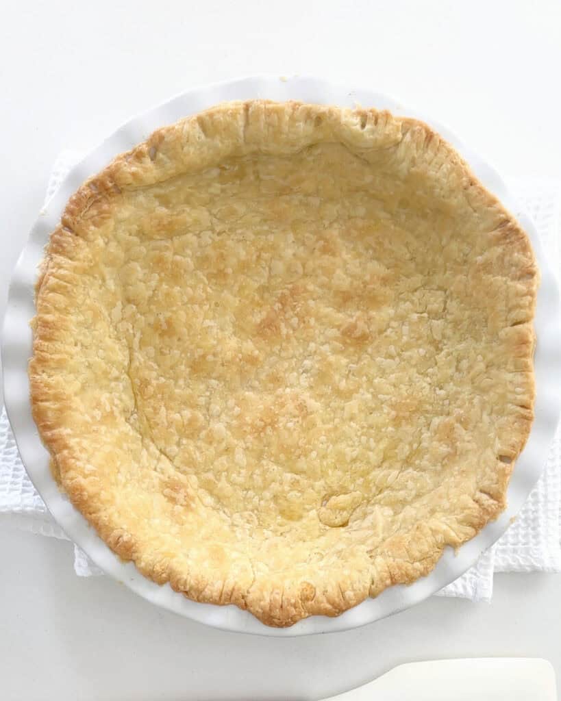 Pre-baked pie crust in a white dish. White surface.