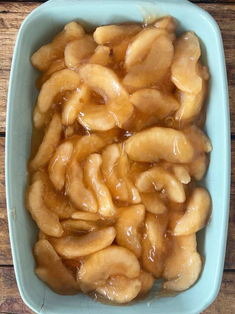 Canned apple pie filling in a rectangular blue baking dish.